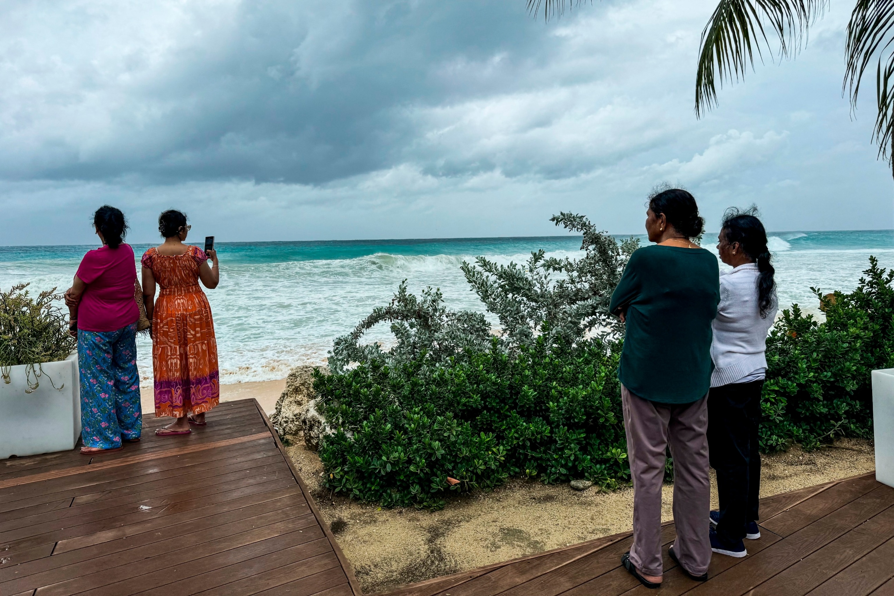 PHOTO: Tourists look at the sea waves as the hurricane Beryl passes near to Bridgetown, Barbados on July 1, 2024.